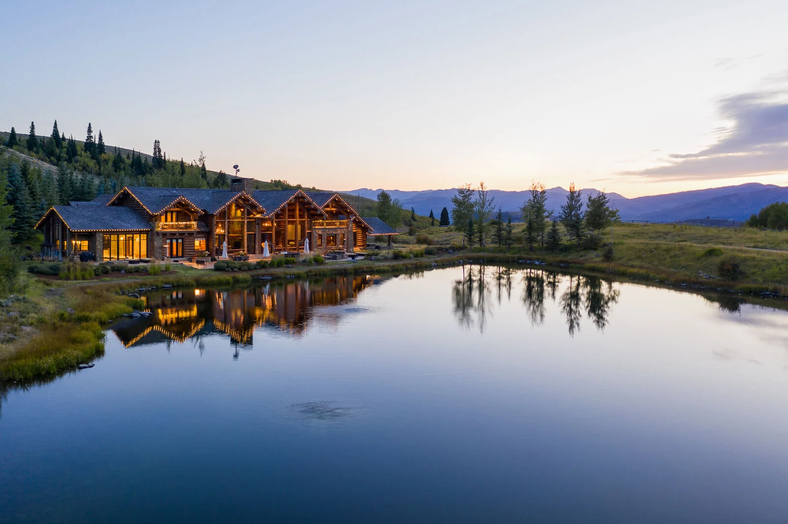 Luxury lakefront cabin nestled on a hillside during sunset at abode jackson hole vacation rentals
